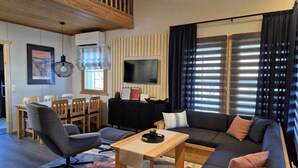 Ett modernt vardagsrum med en soffa, fåtölj, matbord och TV.