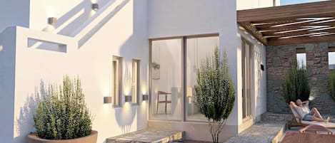 A modern building with a covered patio area, outdoor seating, and potted plants.