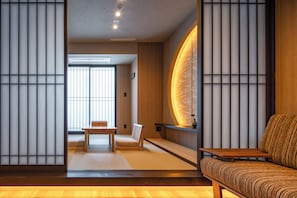 A traditional Japanese room with tatami flooring, a low wooden table, a cushioned bench, and a wall with a circular design. - Anran Hotels&Resorts (OSAKA)