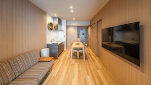 Un interior moderno con un sofá, una mesa de comedor y un televisor montado en la pared.