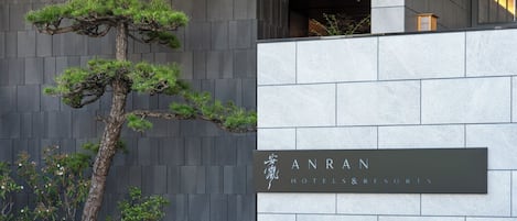 Une façade moderne, ornée d’un grand bonsaï et d’une enseigne indiquant « ANRAN HOTELS & RESORTS ».