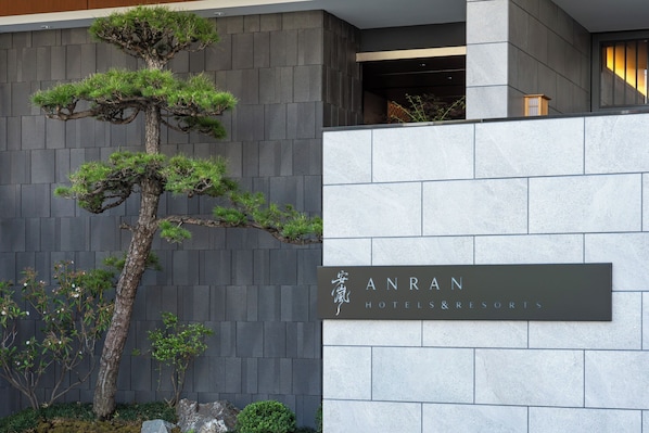 A modern building facade with a large bonsai tree and a sign for 'ANRAN HOTELS & RESORTS'. - Anran Hotels&Resorts (OSAKA)