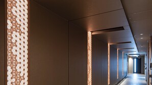 Un pasillo moderno de hotel con un largo recorrido recto, iluminación empotrada y paneles decorativos en la pared.