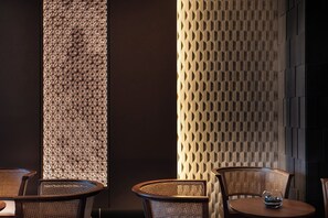 A room with two chairs and a table, a decorative wall with geometric patterns, and a textured wall with a diamond pattern. - Anran Hotels&Resorts (OSAKA)