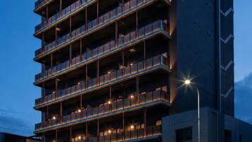 A multi-story hotel with balconies, a ground-level entrance, and a sign with Japanese characters.
