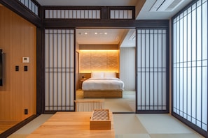 A traditional Japanese-style bedroom with tatami flooring, a bed with white bedding, and a sliding shoji screen door.