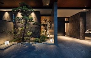 A modern building with a stone facade, a large tree, and a well-lit entrance area. - Anran Hotels&Resorts (OSAKA)