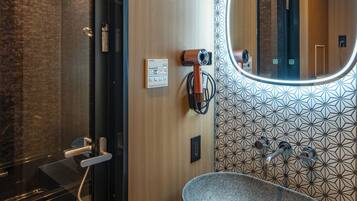 Un baño moderno con una bañera independiente, un espejo grande y un revestimiento de pared con diseño geométrico.