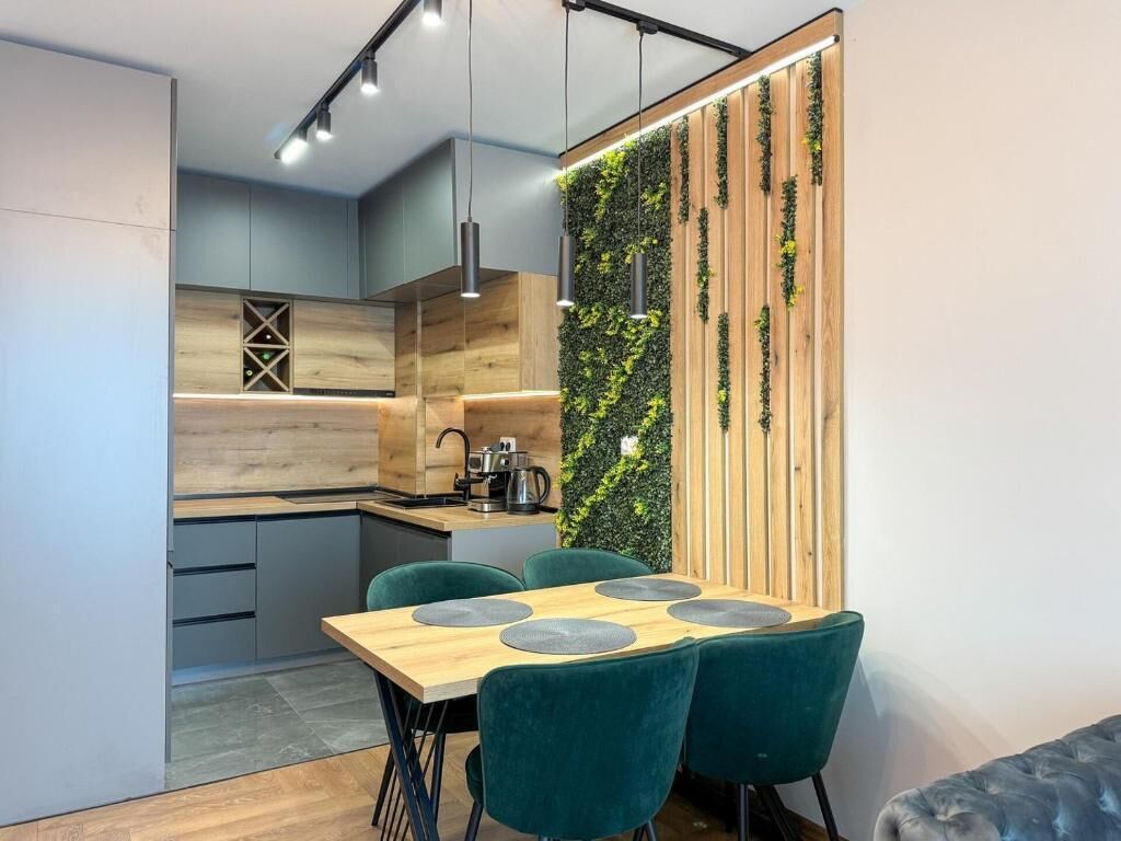 Eine moderne Küche mit einer Holz-Arbeitsplatte, einem eingebauten Herd und einer grünen, vertikalen Wandbegrünung.