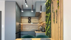 Uma cozinha moderna com bancada de madeira, cadeiras verdes e iluminação pendente.