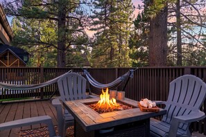A deck with a fire pit, two chairs, and a hammock. - Hot Tub + Game Room + Firepit • Near Bear Mountain + Lake | Balboa Big Bear (Big Bear Lake)