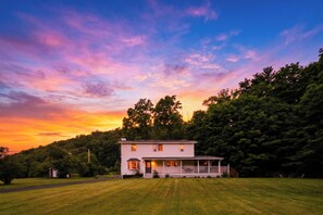 A two-story house with a porch and a lawn in front. - Firepit + Grill + Chef Kitchen | Creek + Waterfalls | Ohana Nature Escape (Catskill)