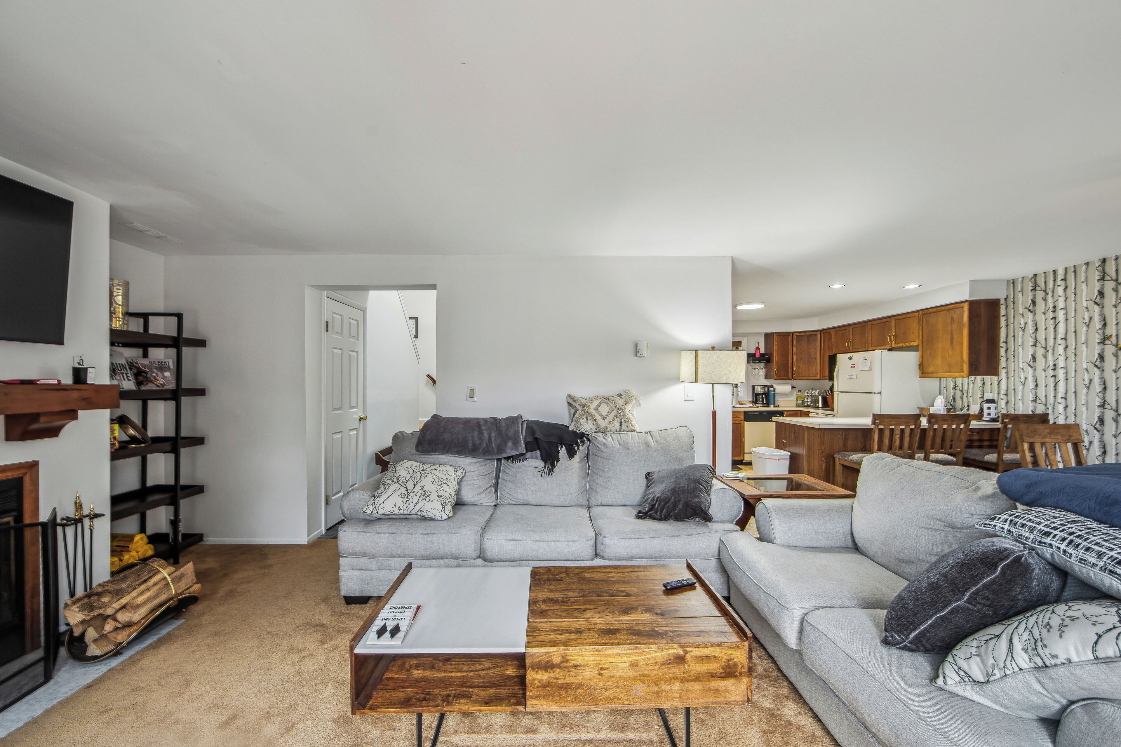 A living room with a grey sofa, a wooden coffee table, and a fireplace.