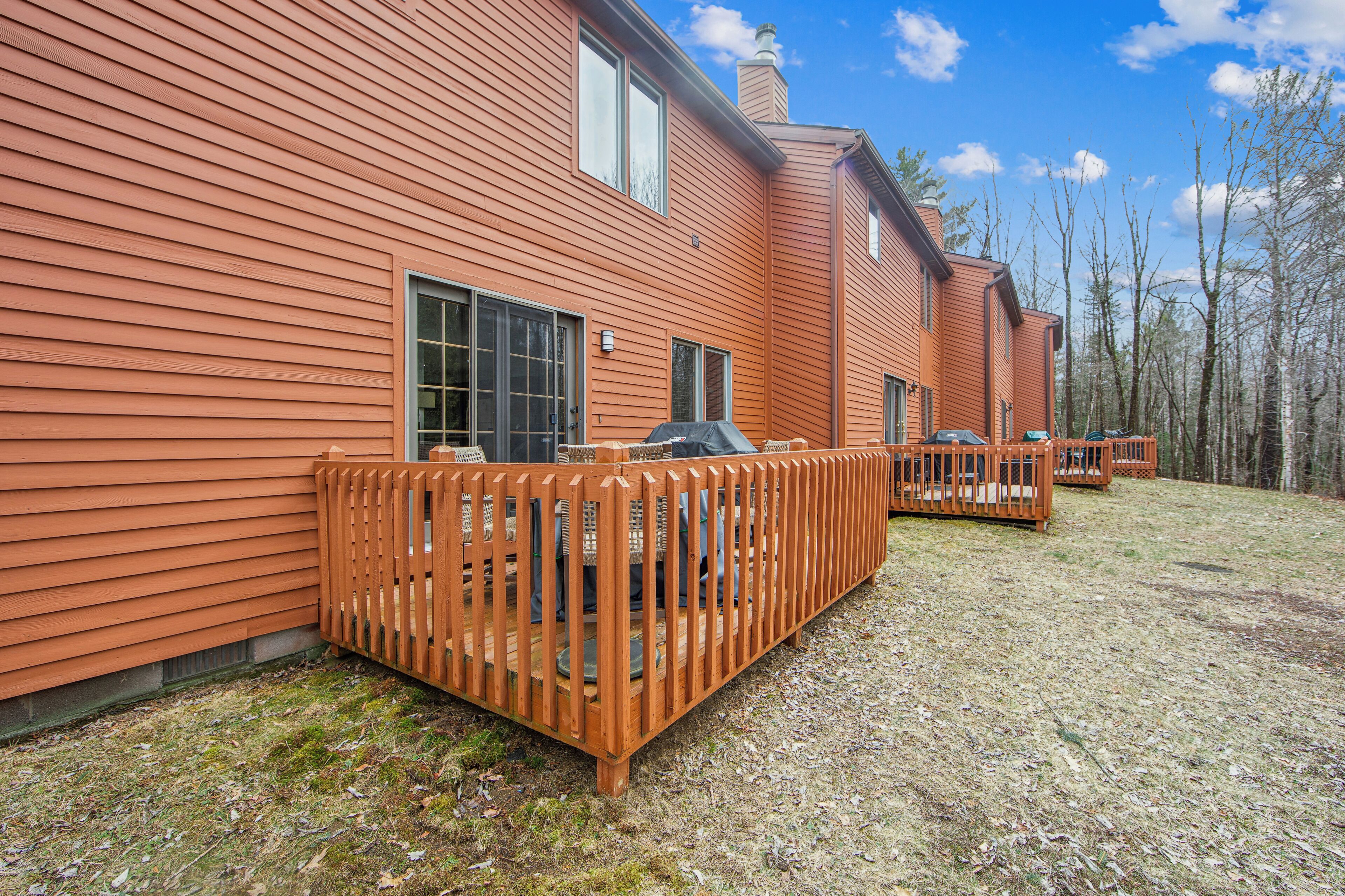 A two-story house with a wooden deck and a covered outdoor seating area.