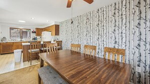 A modern kitchen with wooden cabinets, a dining table, and a ceiling fan. - 2 Townhomes + Indoor Pool + Game Room | Gore Mtn | The Summit at Gore Mtn (North Creek)