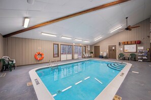 En inomhuspool med tydliga markeringar för banorna, en takfläkt och en flytväst som hänger på väggen.