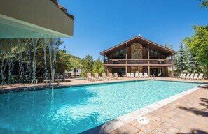 Ein Schwimmbecken mit Liegestühlen und ein Gebäude mit Balkon im Hintergrund.