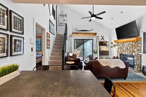 Ein modernes Wohnzimmer mit Kamin, Essbereich und einer Treppe, die zu einer anderen Ebene führt.