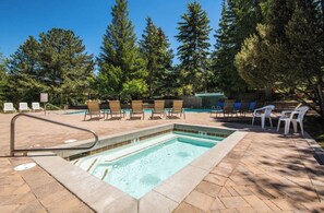A rectangular pool with a hot tub, surrounded by lounge chairs and a brick deck. - Vaulted Ceilings + Gas BBQ Deck | Walk to Lift + Trails | Cabriolet Chalet (Park City)