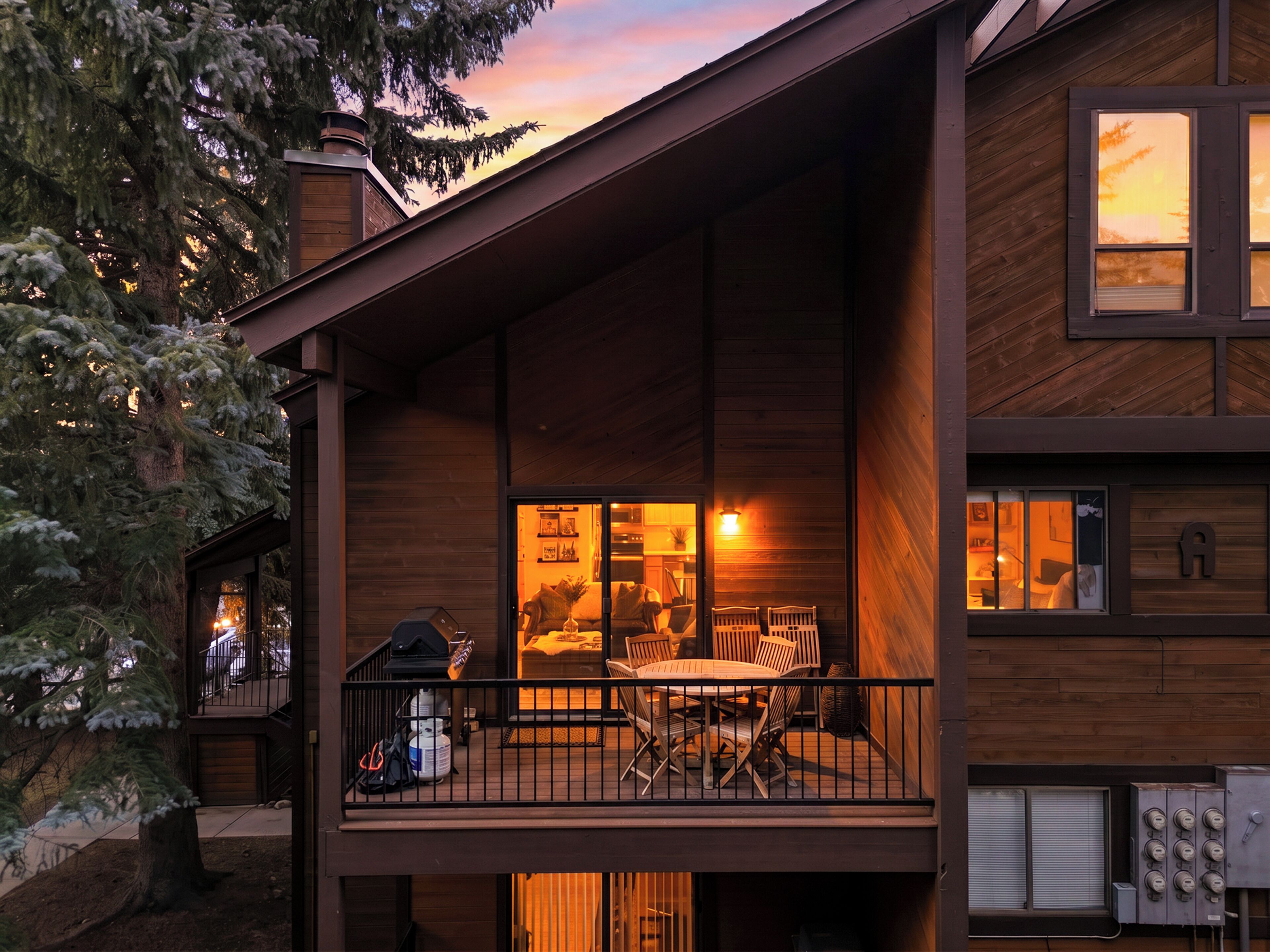 Une cabane en bois dotée d’un balcon, d’un espace extérieur aménagé pour s’asseoir et d’une cuisine ouverte.