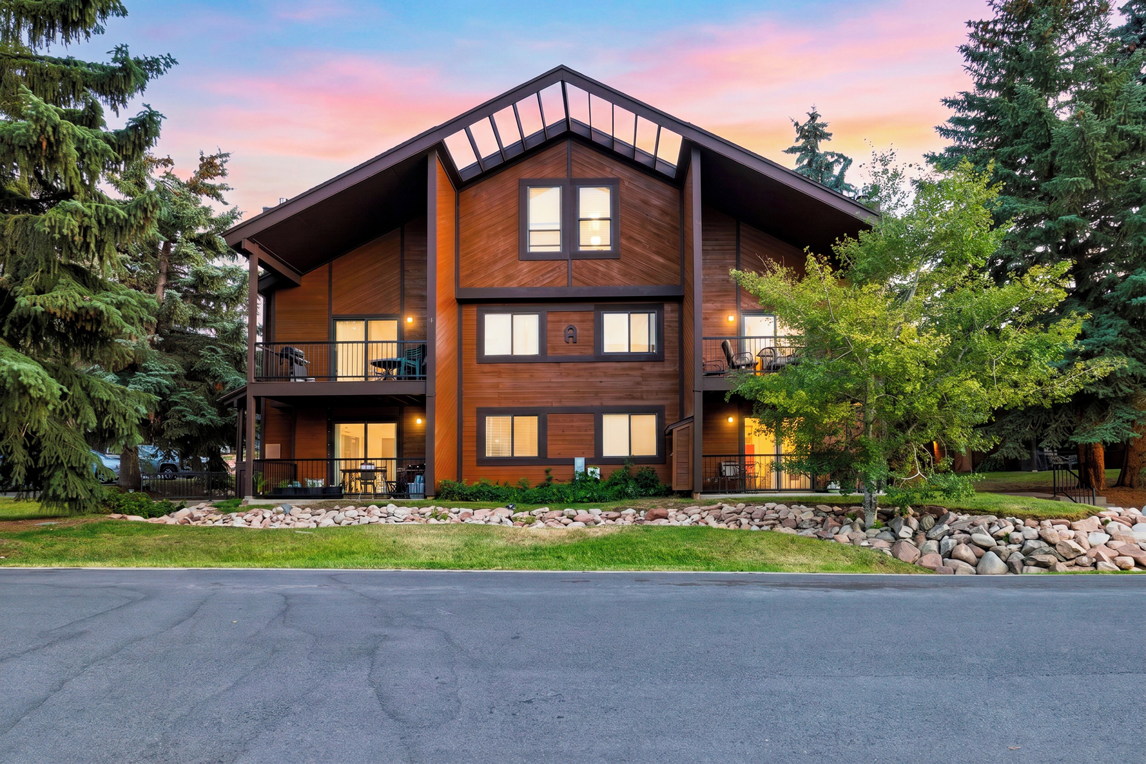 A modern multi-story building with a wooden facade, large windows, and a balcony on the second floor.