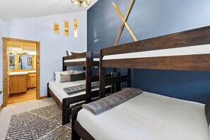 Quarto com beliches, porta de madeira, espelho e luminária fixada na parede.