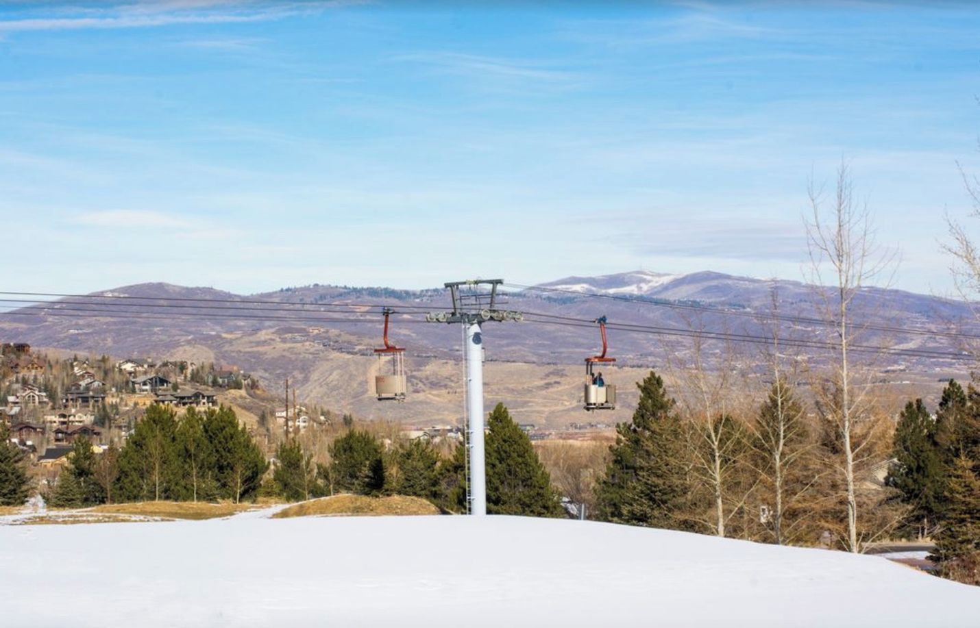 A ski lift with cabins and a cable system against a mountainous backdrop.