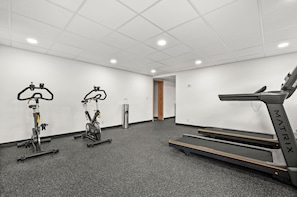 Ein Fitnessraum mit Ergometer, Laufband und Wasserspender.