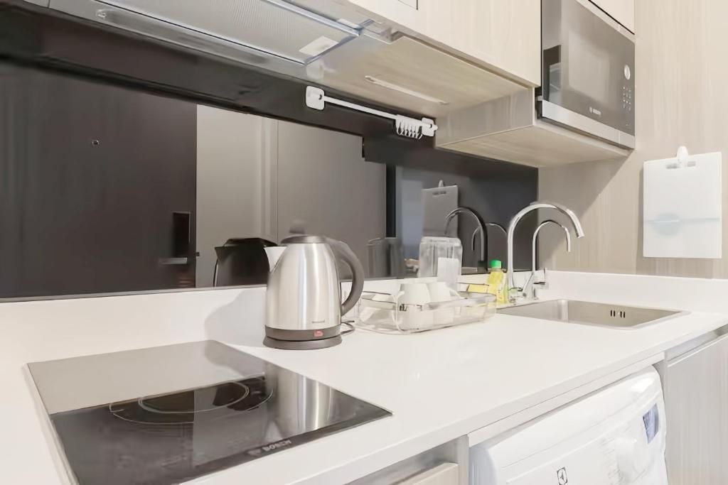 A modern kitchen with a built-in stove, a kettle, a coffee maker, and a sink.
