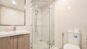 Ein modernes Badezimmer mit einer gläsernen Duschkabine, einer weißen Toilette und einem hölzernen Waschtisch.