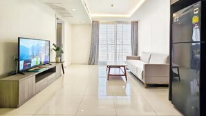 Ein modernes Wohnzimmer mit Flachbildfernseher, Sofa, Couchtisch und Kühlschrank.