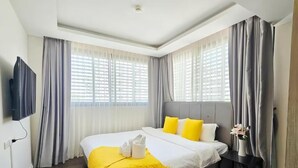 Ein Hotelzimmer mit einem großen Bett, einem Flachbildfernseher und einem Fenster mit Vorhängen.