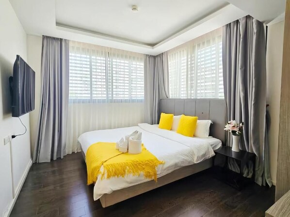 Quarto de hotel com uma cama grande, televisão de tela plana e uma janela com cortinas.