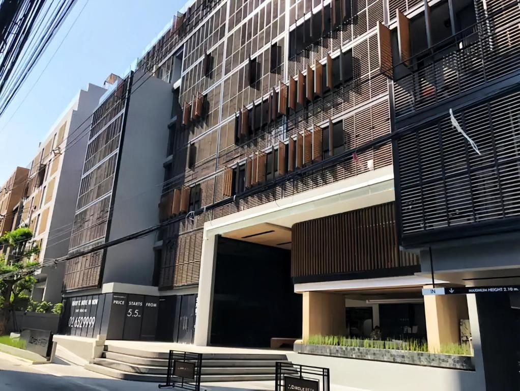 A multi-story building with a modern architectural design, featuring a prominent entrance with steps leading up to a covered area.