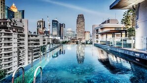Una piscina en la azotea con vistas a un paisaje urbano, rodeada de edificios altos.