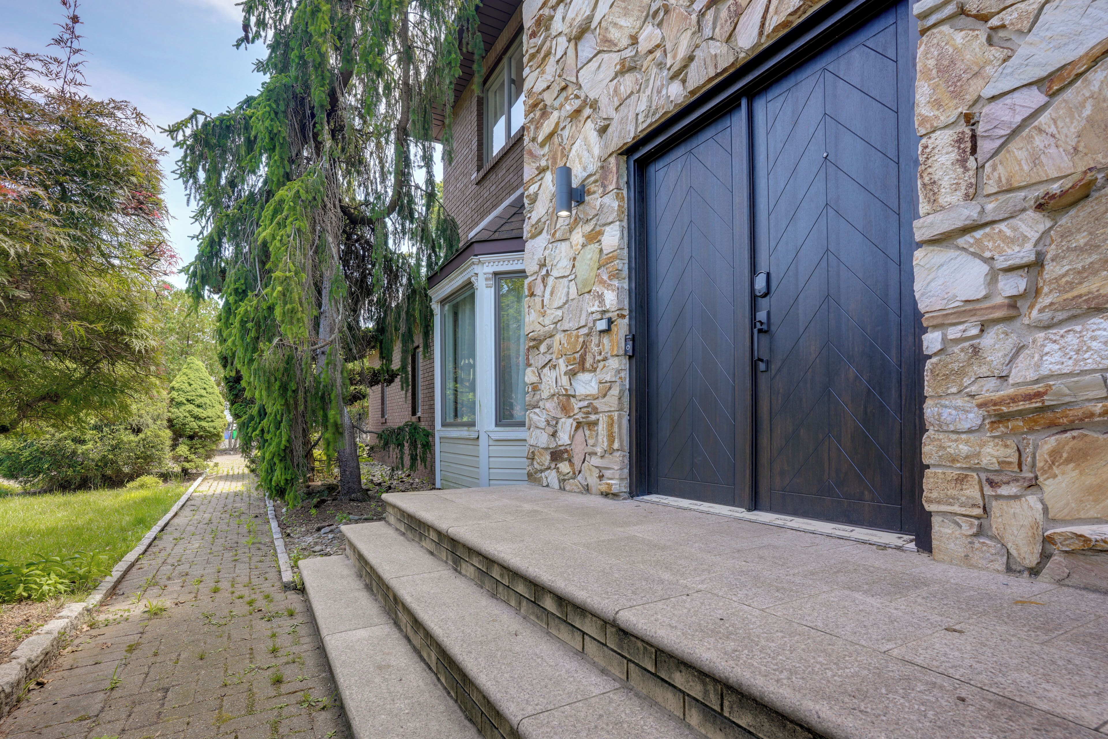 A residential property with a stone facade, a garage door, and a pathway leading to the entrance.