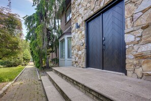Il s'agit d'une propriété résidentielle dotée d'une façade en pierre, d'une porte de garage et d'un chemin menant à l'entrée.