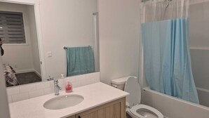 A bathroom with a sink, toilet, and shower curtain. - Spacious 3BR Townhouse in SE Calgary – Perfect for Families & Groups (Calgary)
