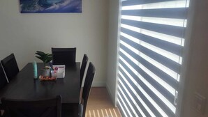 A dining area with a table, chairs, a potted plant, and a window with blinds. - Spacious 3BR Townhouse in SE Calgary – Perfect for Families & Groups (Calgary)