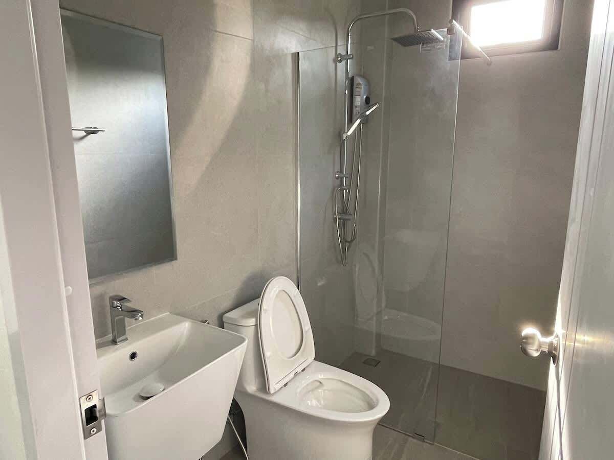 A modern bathroom with a white sink, toilet, and glass-enclosed shower.