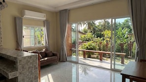Un amplio salón con un gran ventanal corredera que da a un jardín.