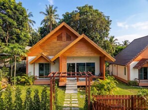 A modern house with a wooden facade, large windows, and a garden with palm trees. - Triangle Villa (Ko Pha-ngan)