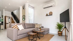Een moderne woonkamer met een modulaire bank, een ronde salontafel en een flatscreen televisie.