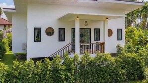 Une maison moderne à deux étages, dotée d’un porche abrité, d’un escalier et d’un jardin bien entretenu.