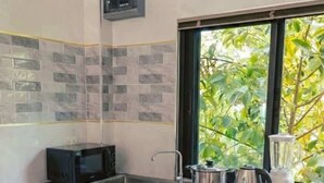 Une cuisine moderne équipée d’un four à micro-ondes, d’une cuisinière, d’une bouilloire et d’un mixeur, le tout posé sur le plan de travail.