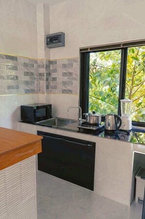 A modern kitchen with a microwave, stove, kettle, and blender on the countertop.