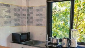 Uma cozinha moderna com micro-ondas, fogão, pia e uma janela com vista para o verde.