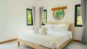 Quarto com cama, cortinas, janela com vista e uma janela redonda acima da cama.