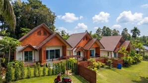 Une rangée de maisons modernes aux toits inclinés, entourées d’une végétation luxuriante et sous un ciel dégagé.