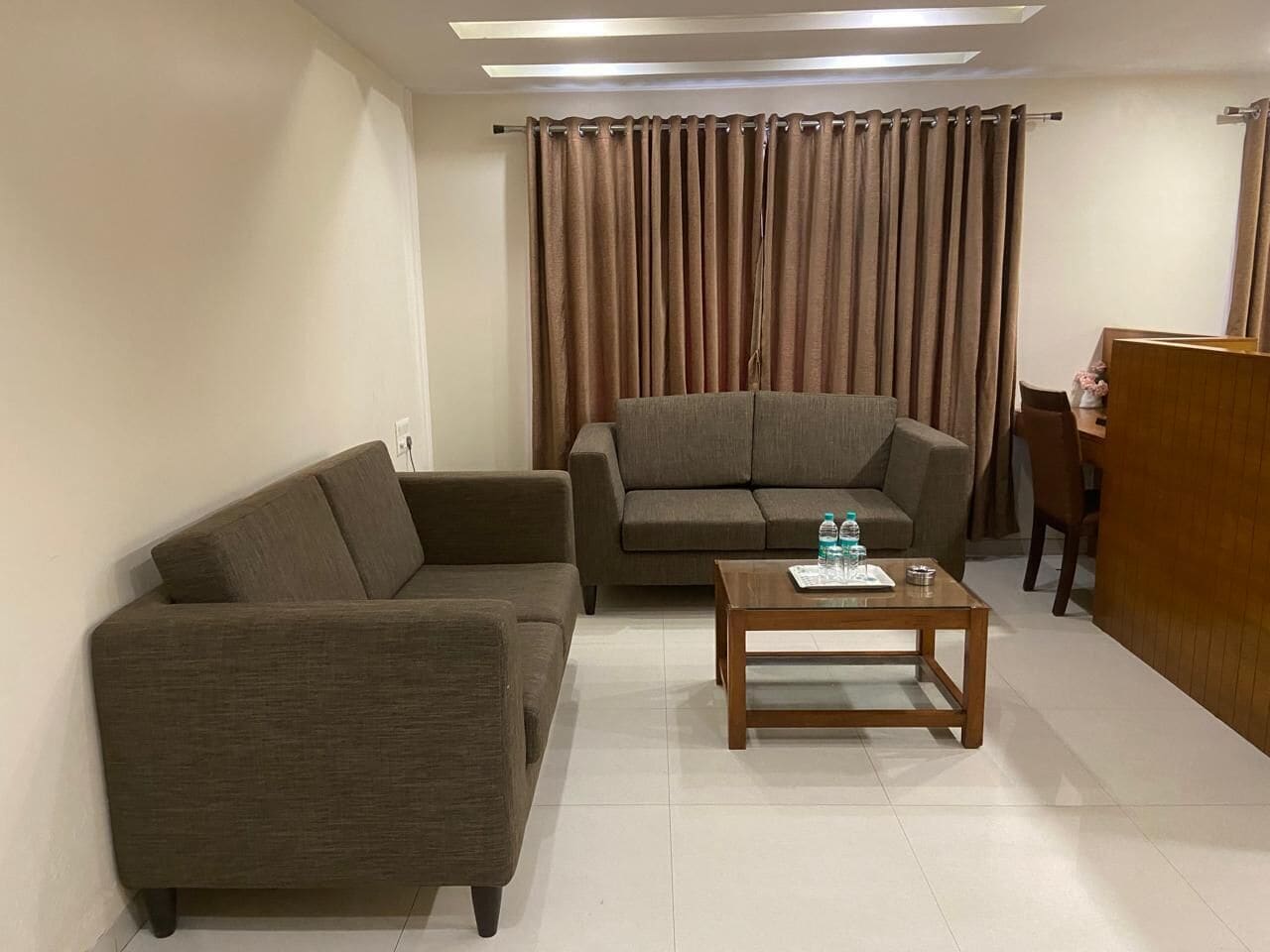 Una sala de estar con dos sofás, una mesa de centro y una cortina.